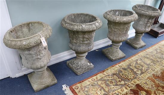 A set of four campana shaped reconstituted garden urns, on square plinths W. 45cm approx.